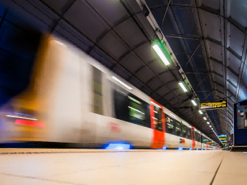 A train passing through a covered rail station beside the platform